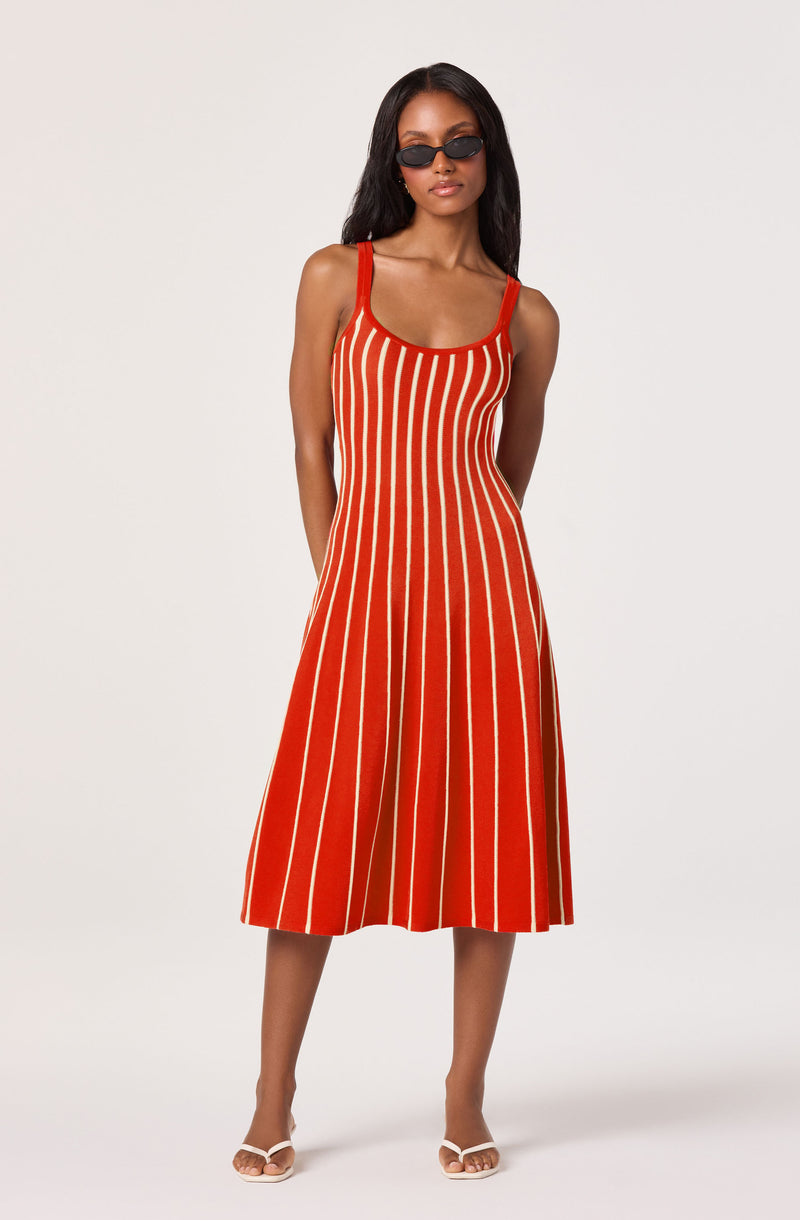 Sleeveless red dress with white vertical stripes, midi length, paired with sunglasses and sandals.