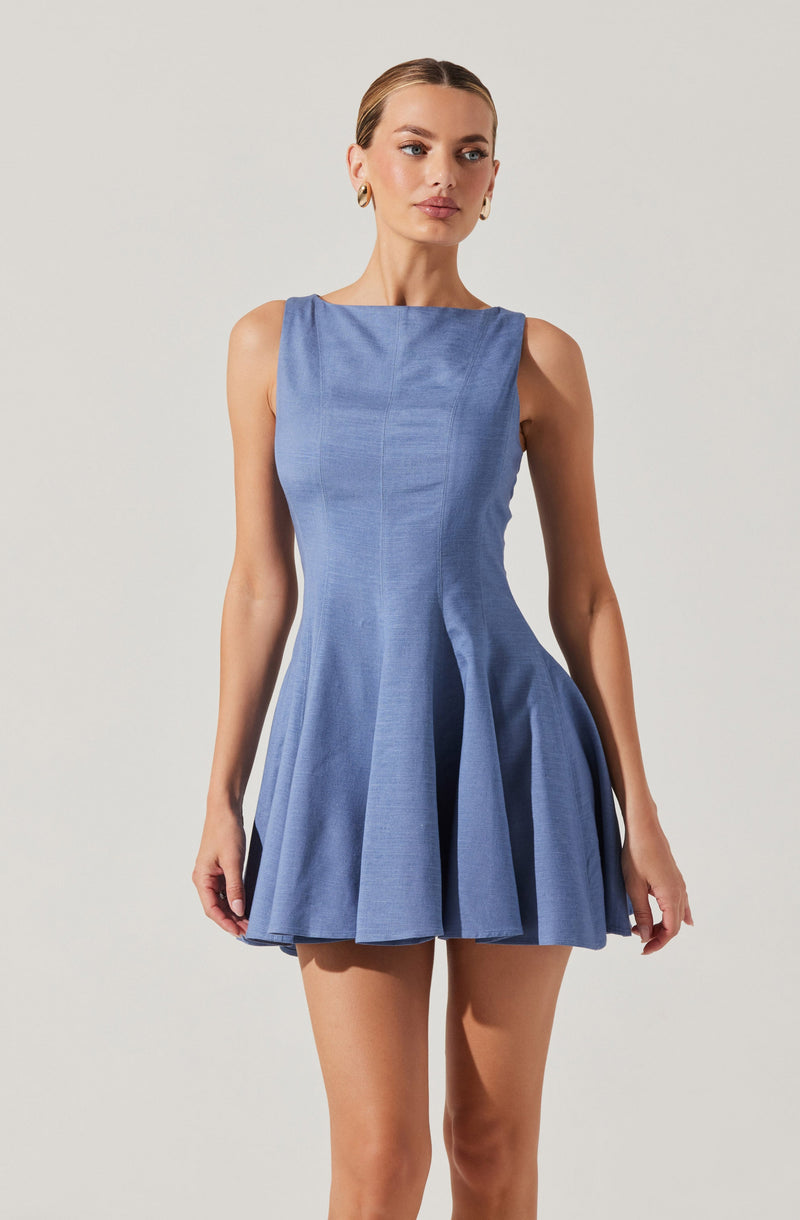 A woman is wearing a sleeveless, light blue dress with a fitted bodice and a flared, pleated skirt. The dress features a high, rounded neckline and has a textured fabric appearance.