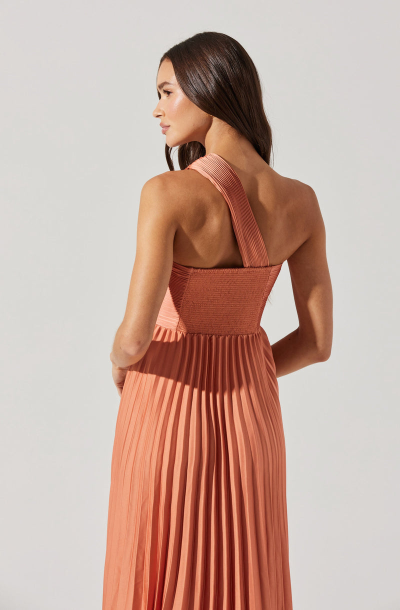 Woman in a peach pleated dress with a one-shoulder strap.