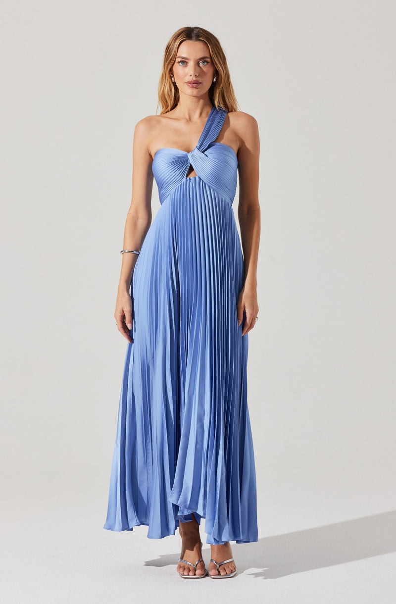 A woman is wearing a long, flowing blue pleated dress with a one-shoulder design. The dress has a twisted knot detail at the bust, creating a small keyhole cutout. The fabric is shiny with vertical pleats, and the dress extends to her ankles. She is also wearing strappy high-heeled sandals.