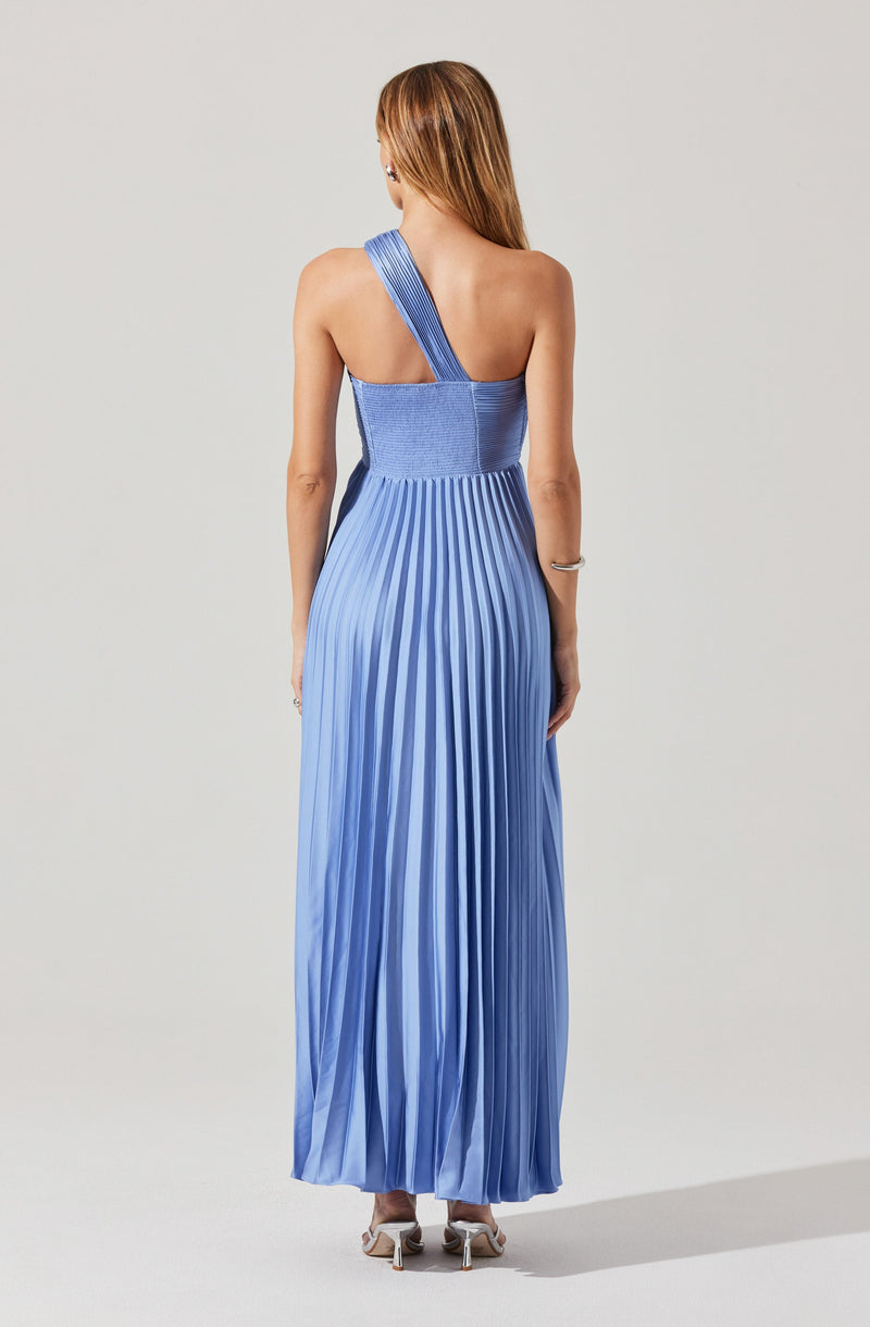 The dress is a floor-length gown made of shiny, pleated fabric in a gradient of blue shades. It features a one-shoulder design with a wide strap over the left shoulder, leaving the right shoulder bare. The fitted bodice transitions into a flowing, pleated skirt that reaches the floor.