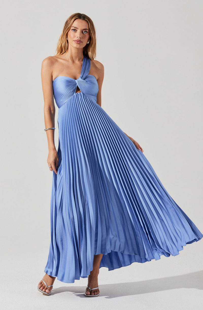 A woman is wearing a sleeveless, floor-length dress in a shiny, light blue fabric. The dress features a twisted knot at the bust with a small cutout below it and a wide shoulder strap on one side. The skirt of the dress is pleated and flows freely to the floor. She is wearing clear, strappy sandals and a bracelet on her right wrist.