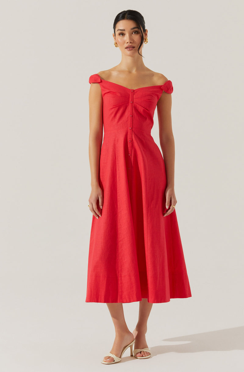 A woman is wearing a red, off-the-shoulder midi dress with short, gathered shoulder straps. The dress features a row of buttons down the front and has a fitted bodice that flares out to a full skirt. She is also wearing beige open-toed heels and gold earrings.
