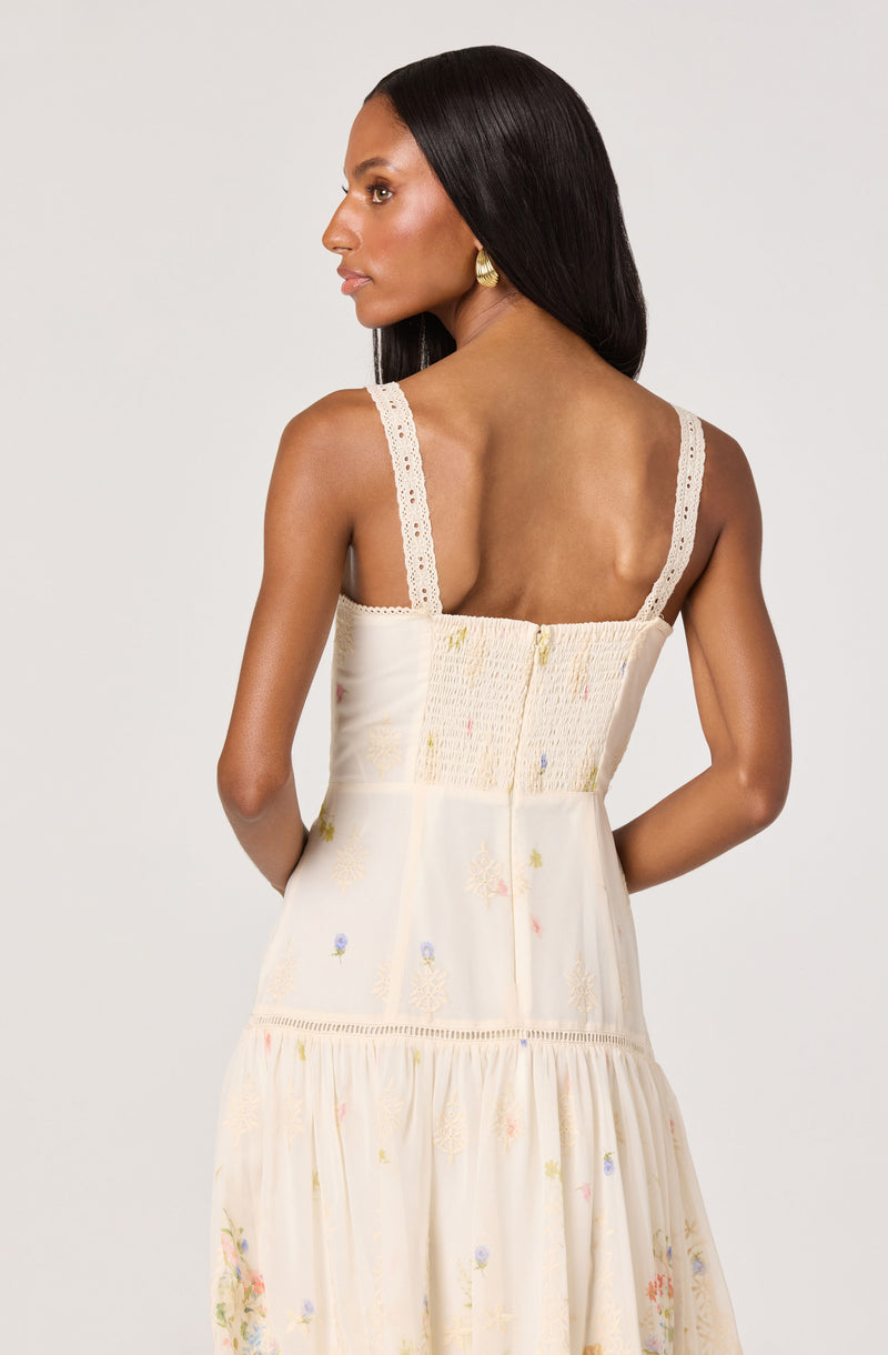 Woman in cream-colored floral dress with lace straps, smocked bodice, and tiered skirt.