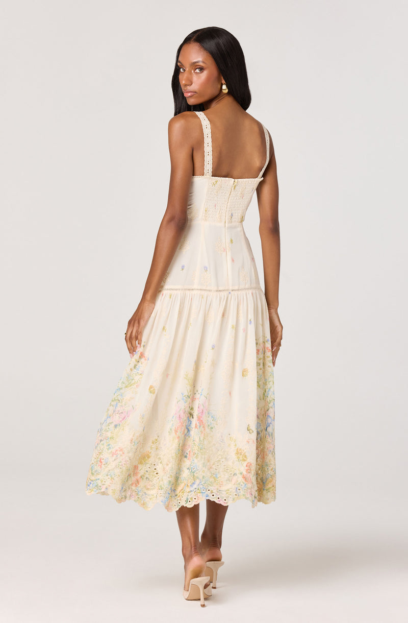 Woman in a cream-colored, embroidered and lace, sleeveless, ankle-length dress.