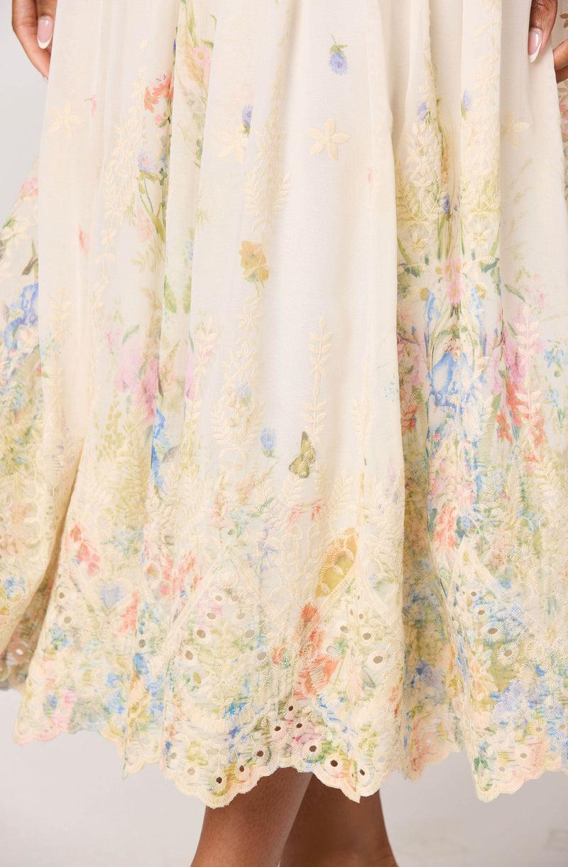 Light-colored dress with floral and embroidery patterns, featuring pastel shades and eyelet hem.