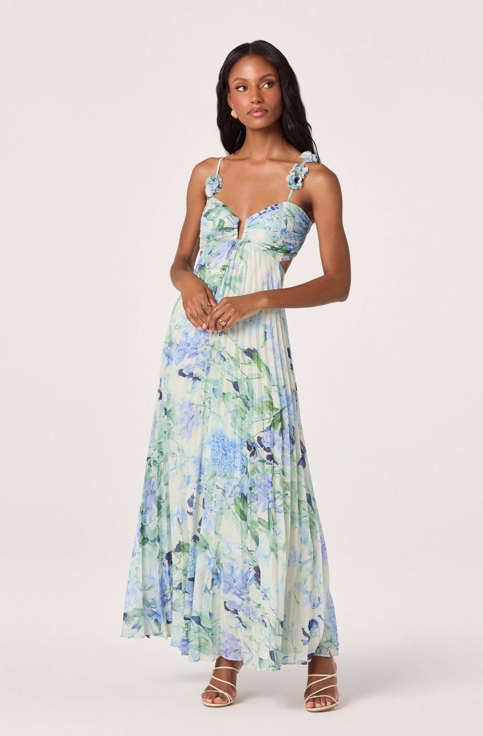 Maxi dress with floral print in blue, green, and white, with shoulder straps decorated with fabric flowers.