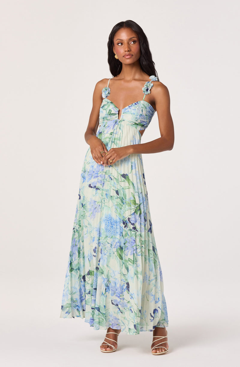 Maxi dress with floral print in blue, green, and white, with shoulder straps decorated with fabric flowers.