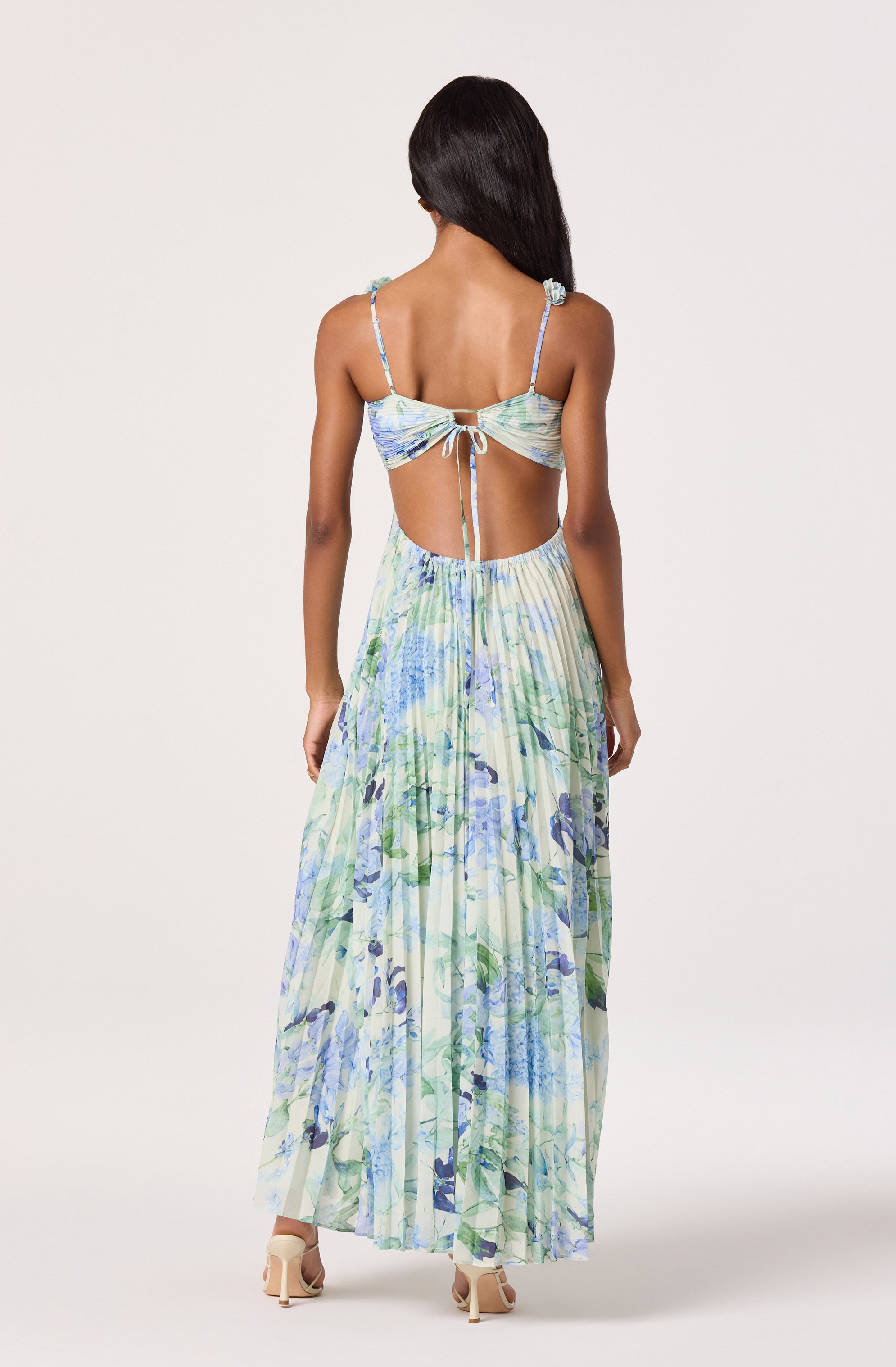 Woman in a flowy, floral maxi dress with a cutout back and spaghetti straps.