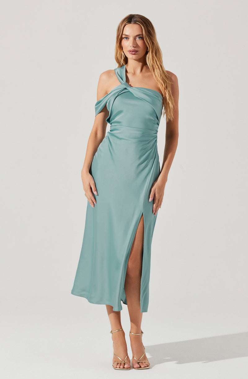 A woman is wearing a light teal, satin evening dress that is off-the-shoulder with a draped neckline and a single strap over one shoulder. The dress has a high slit on one side, revealing part of her leg. She is also wearing nude high-heeled sandals.