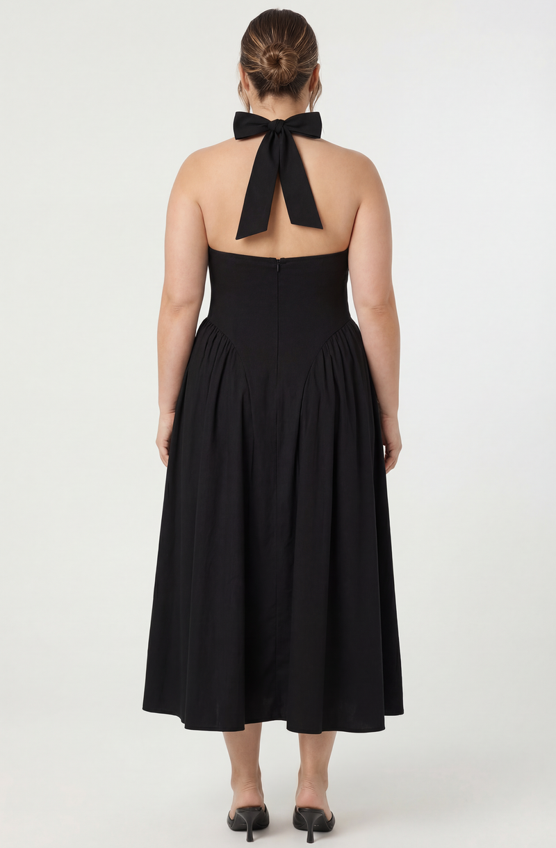 Woman in black strapless dress with a halter neck bow and black heels.