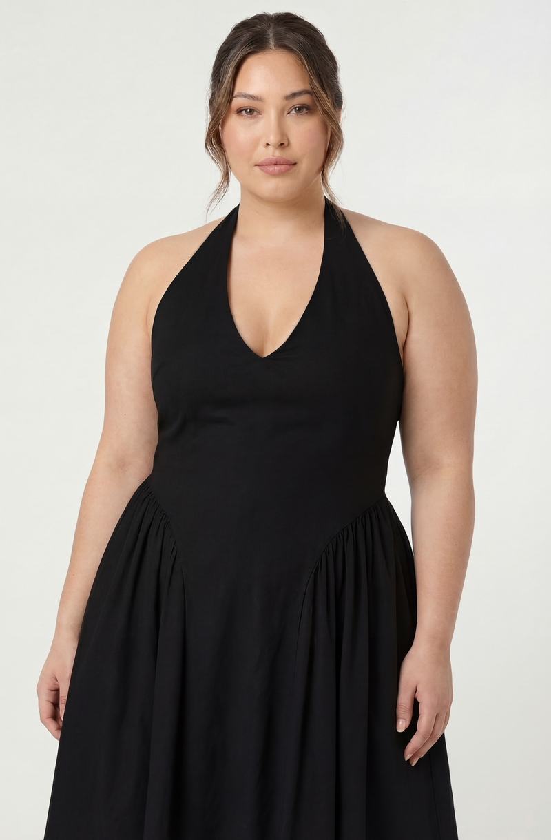 Woman in a black halter dress with a deep neckline and gathered fabric at the waist.