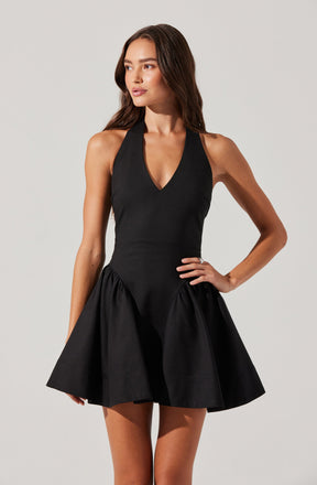 A woman is wearing a sleeveless black dress with a fitted bodice and a deep V neckline. The dress features a flared, gathered skirt that creates a voluminous silhouette.