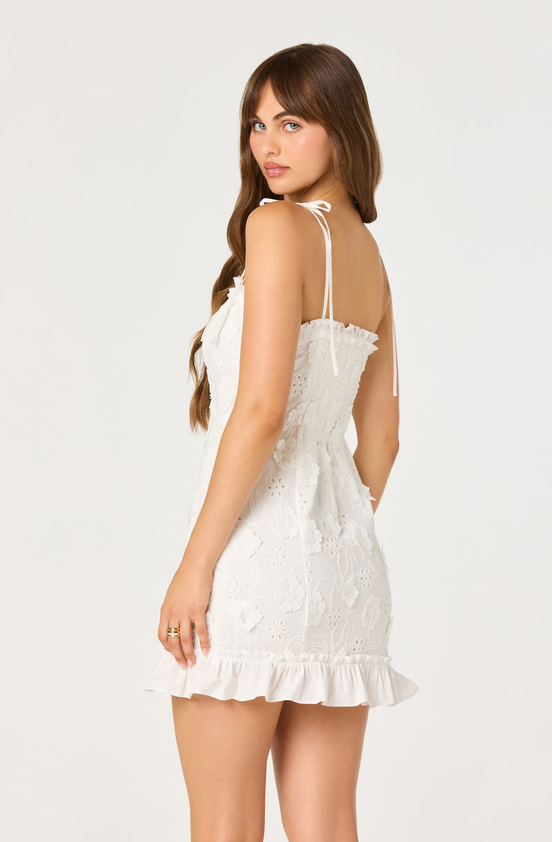 Woman in white lace sundress with ruffle hem and tie straps.