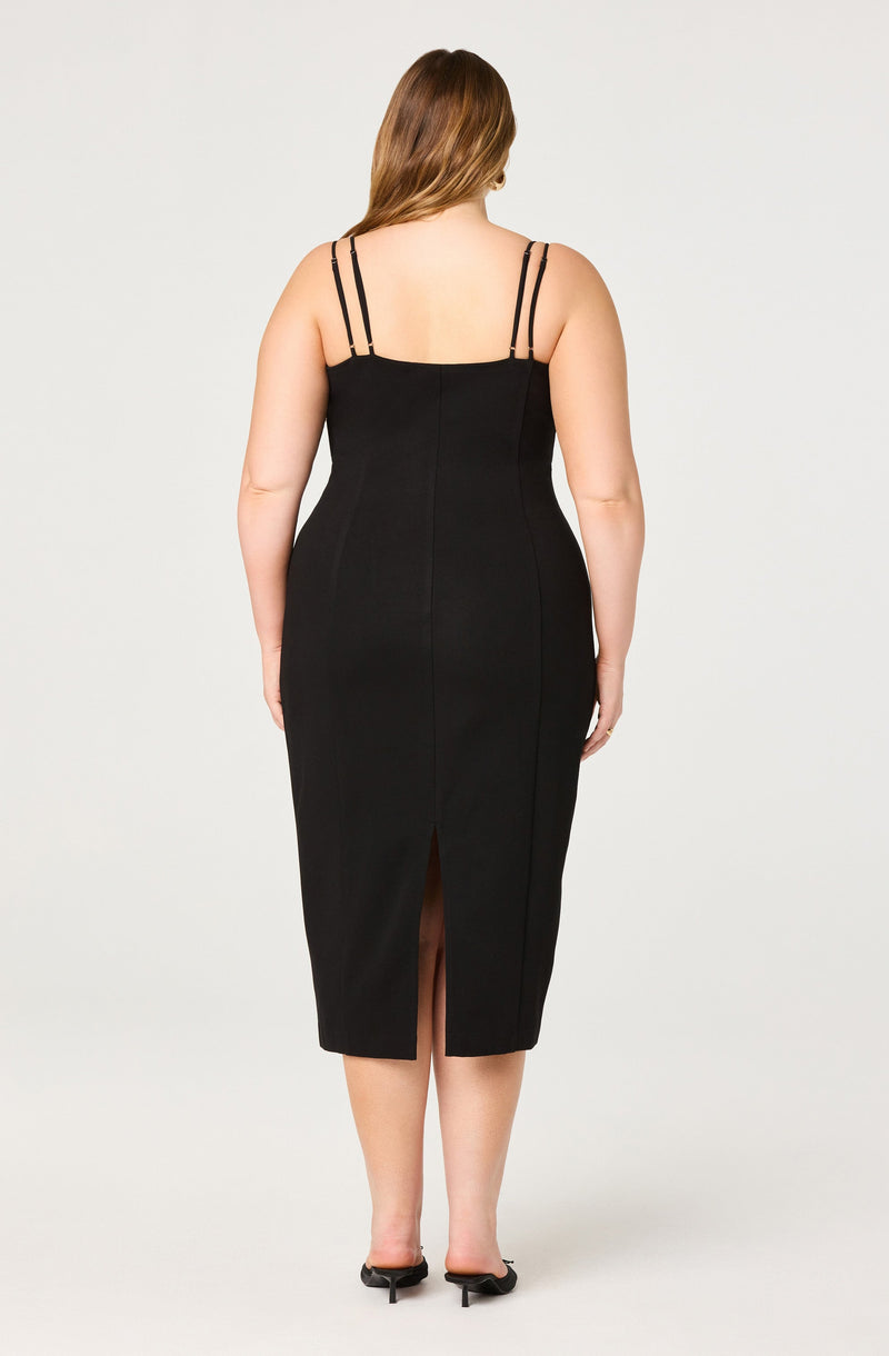 The dress is a form-fitting, sleeveless black midi dress with thin double spaghetti straps. It features a slit at the back hemline.