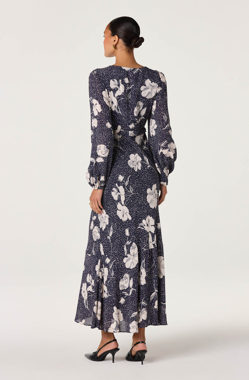 Woman in a long navy floral dress with long sleeves and a flowy skirt.