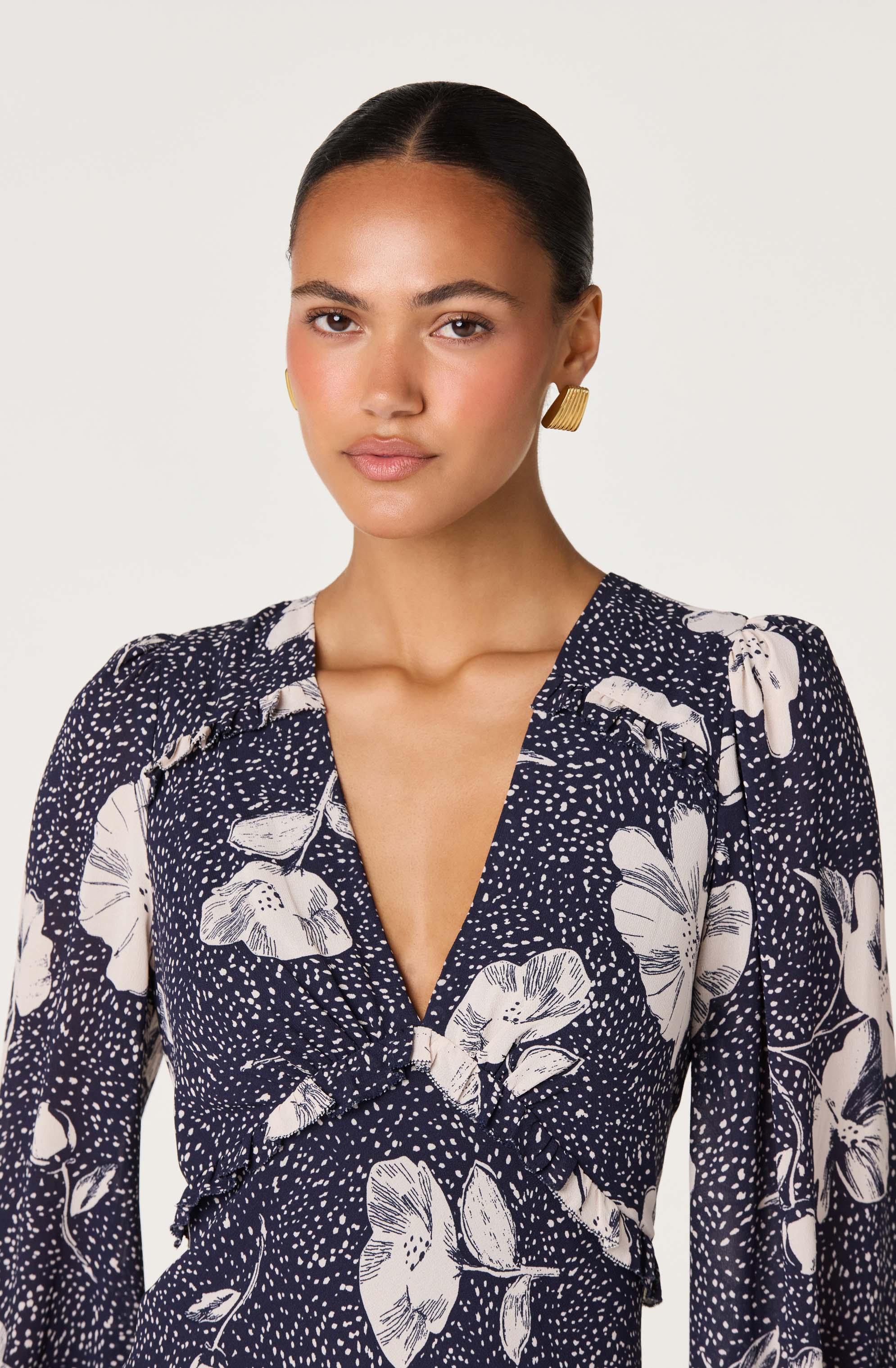 Woman wearing a navy blue and white floral patterned dress with puffed shoulders.