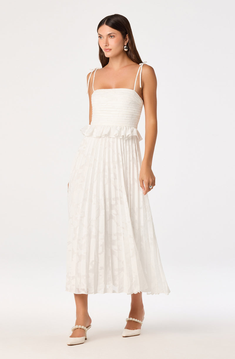 Woman in a white, pleated, sleeveless dress with thin shoulder straps.