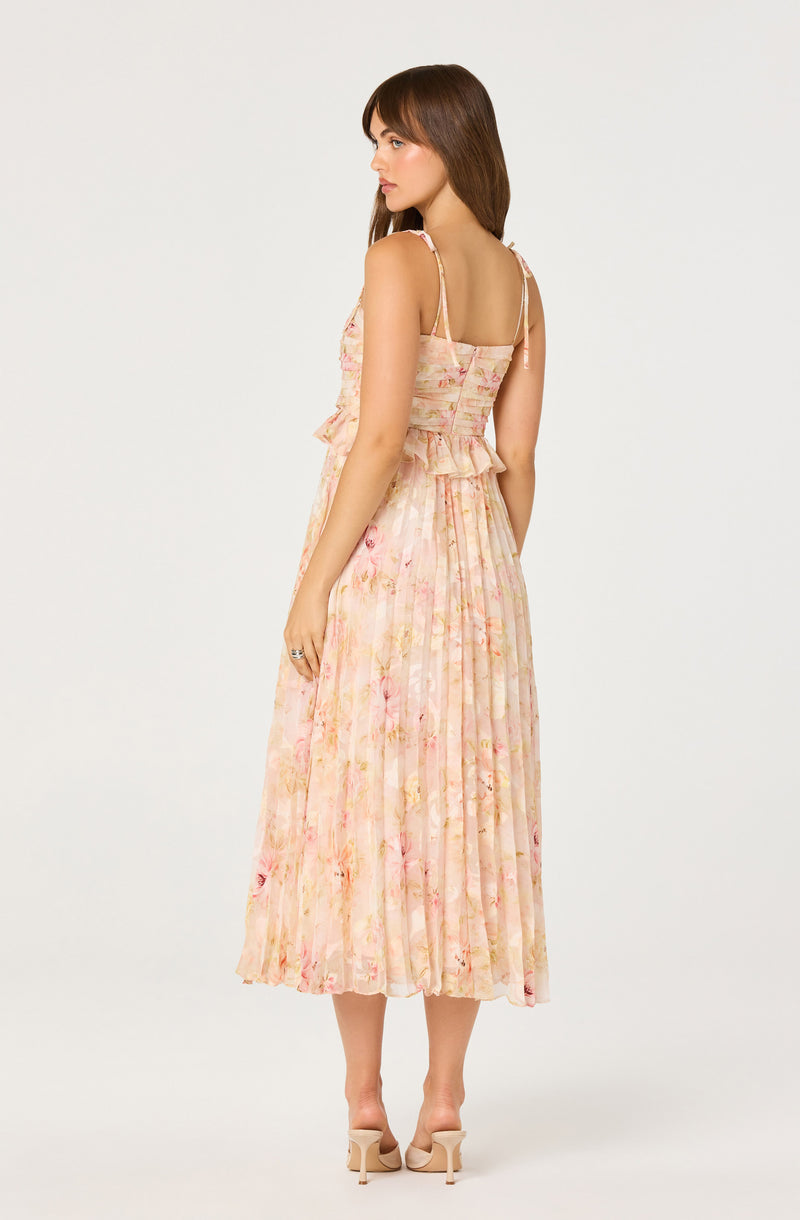 Woman in a flowy, pastel floral dress with ruffles and spaghetti straps, wearing nude heels.