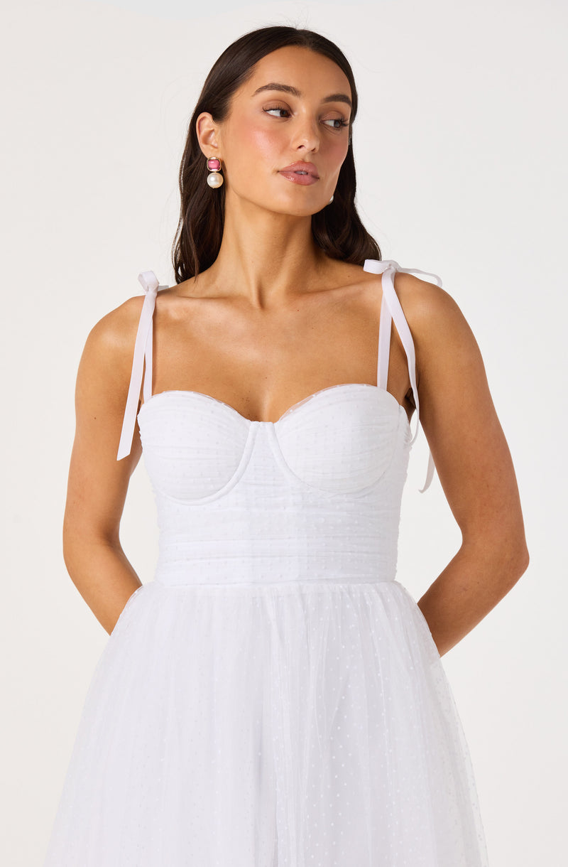 Woman wearing a white sleeveless dress with tie straps on shoulders.