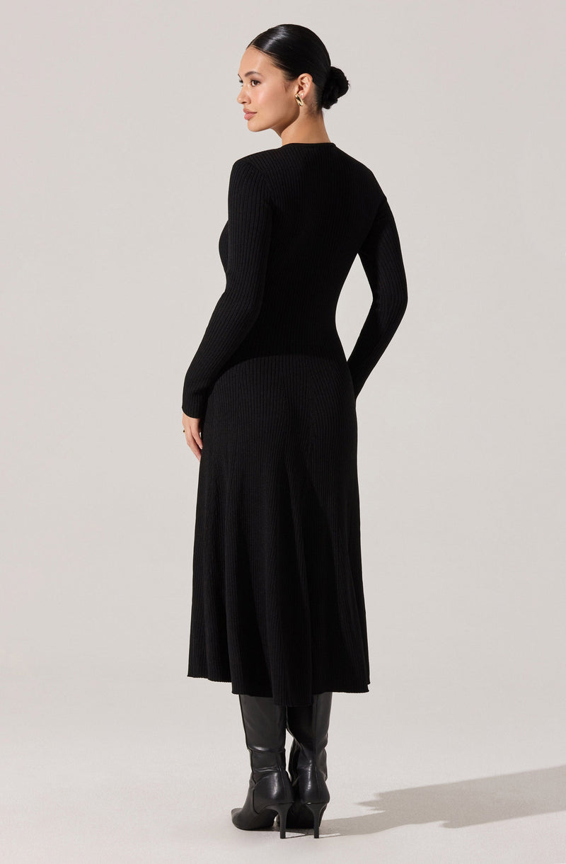 A woman is wearing a fitted, long-sleeve, ribbed black sweater paired with a matching ribbed black midi skirt. She is also wearing tall black leather boots with high heels. The outfit appears elegant and monochromatic.