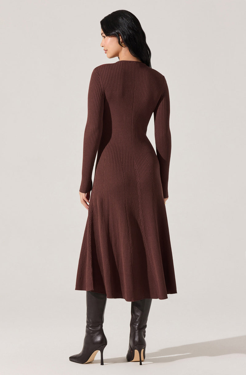 A woman is wearing a long, ribbed, chocolate brown dress with long sleeves and a fitted waist that flares into a flowing skirt. She is also wearing tall, pointed-toe black high-heeled boots.
