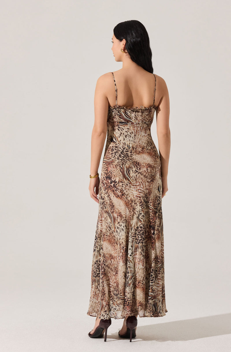 A woman is wearing a full-length, sleeveless dress with thin, spaghetti straps. The dress features an animal print pattern in shades of brown, beige, and black, resembling a mix of leopard and zebra prints. It has a fitted bodice and a flowing skirt.