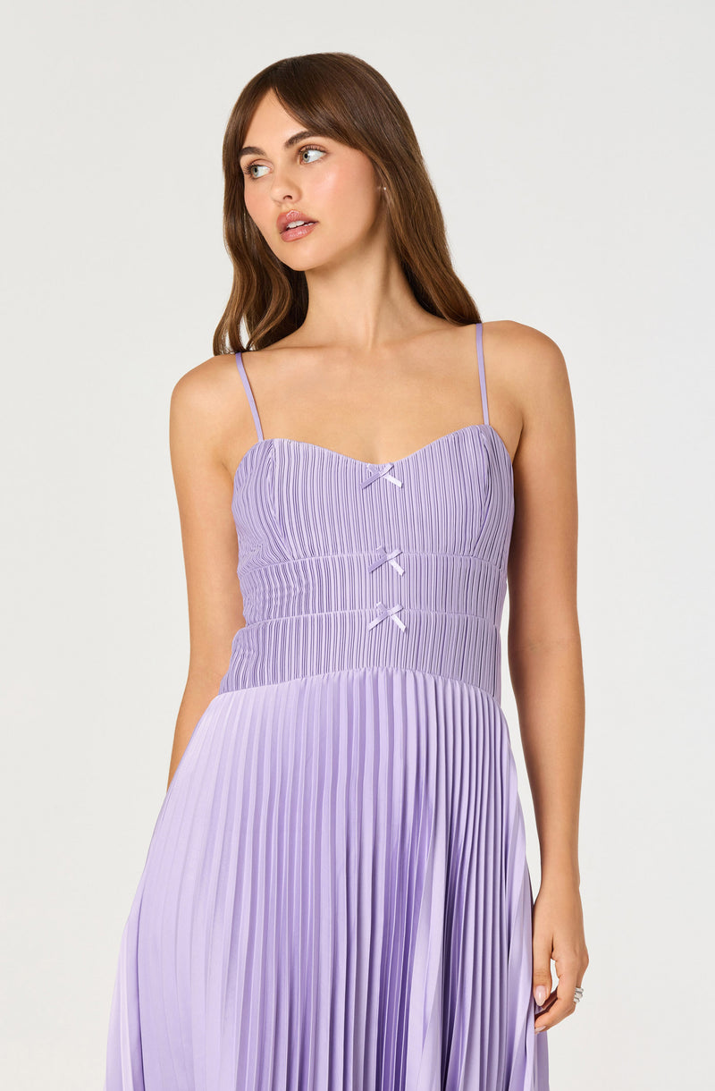 Woman in a lavender pleated dress with spaghetti straps and small bows on the bodice.