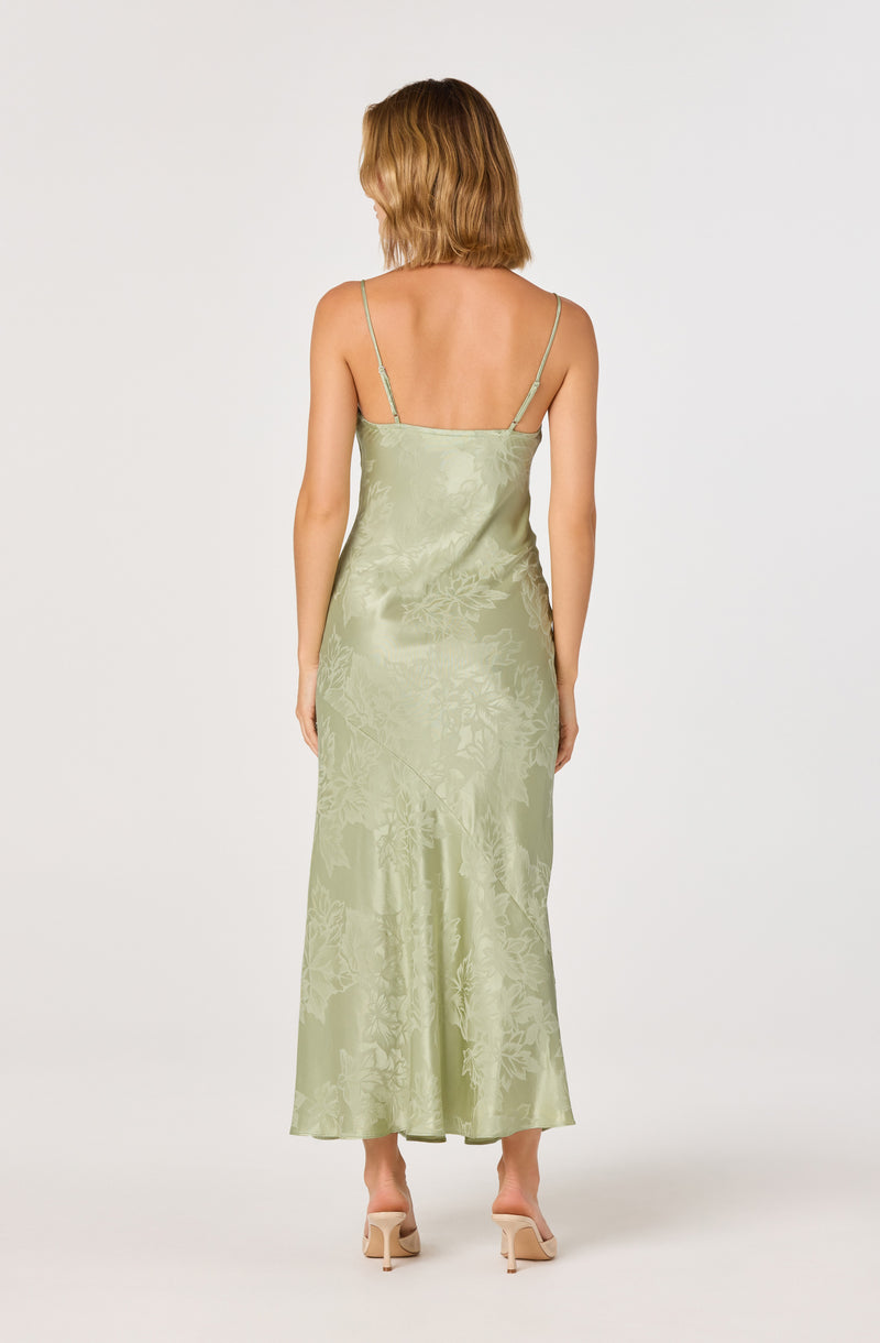 Light green satin slip dress with thin spaghetti straps, floral pattern, and a long, flowing length.