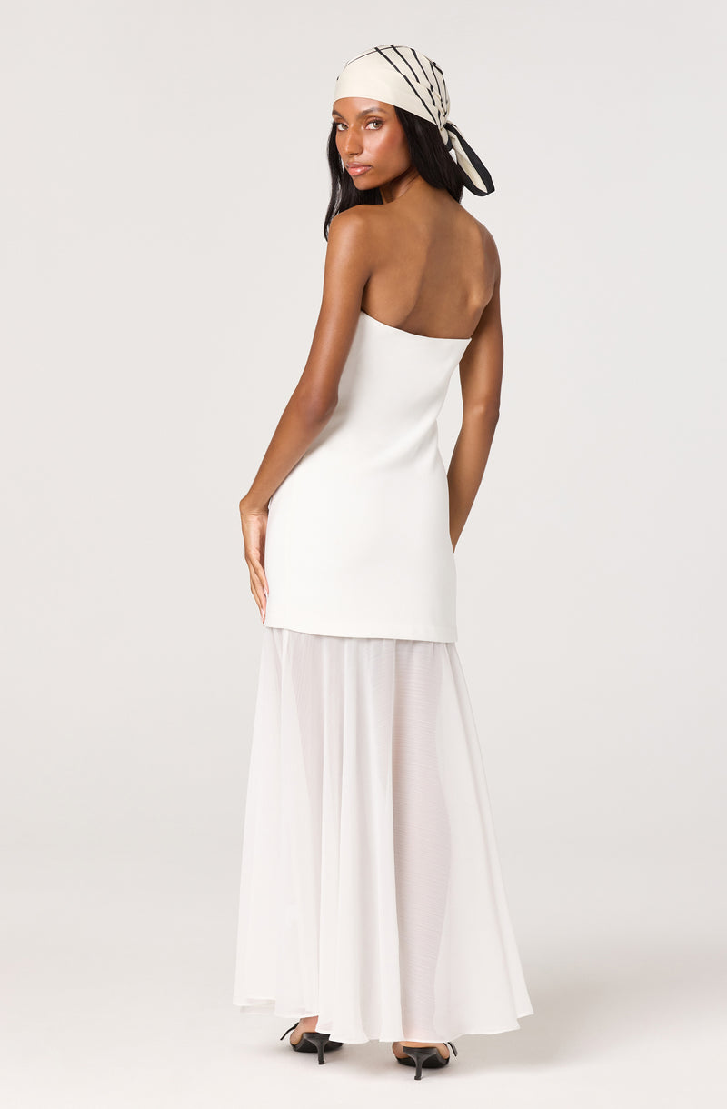 Woman in a strapless white top, long white pleated skirt, and a striped headscarf.