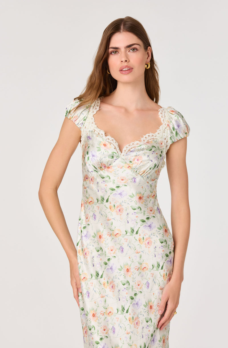 Woman in a floral print dress with puffed sleeves and lace trim on the neckline.