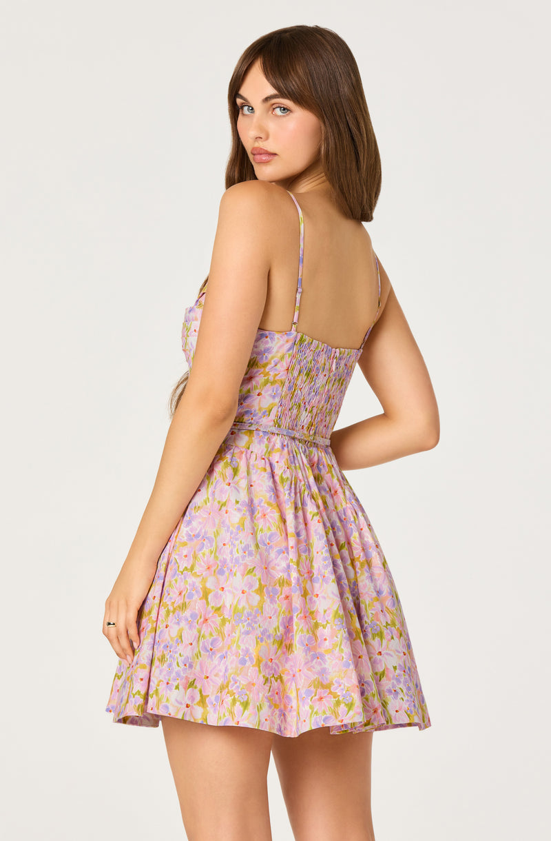 Woman wearing a pastel floral dress with spaghetti straps and an elastic smocked bodice.