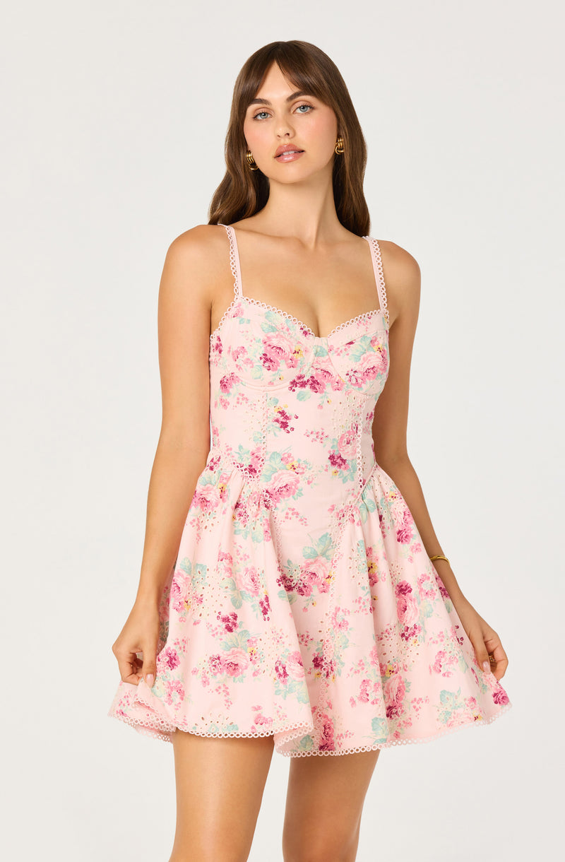Woman wearing a pink floral dress with spaghetti straps and lace trim.