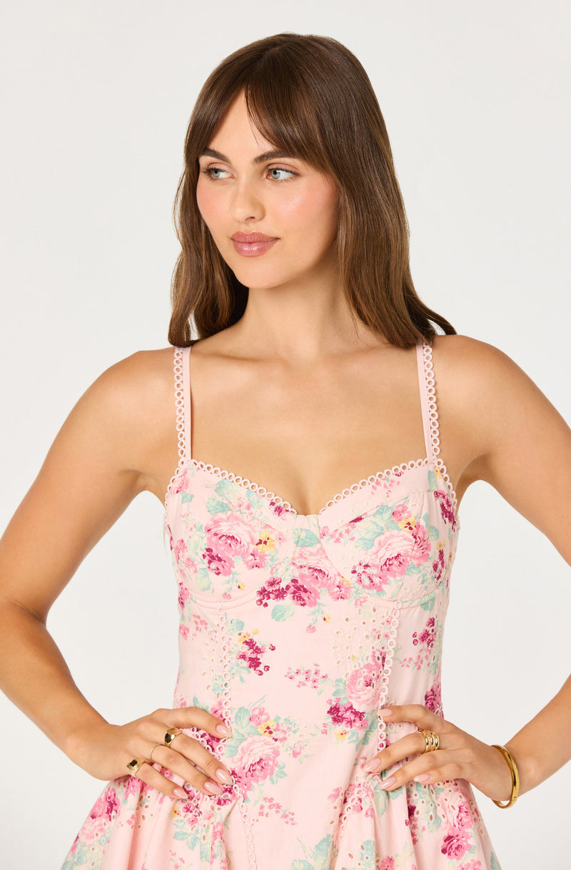 Woman in a pink floral slip dress with thin, decorative straps and lace trim.