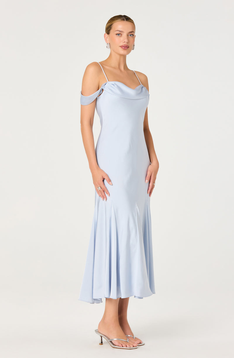 Woman in a light blue satin dress with off-the-shoulder sleeves, spaghetti straps, and high heels.