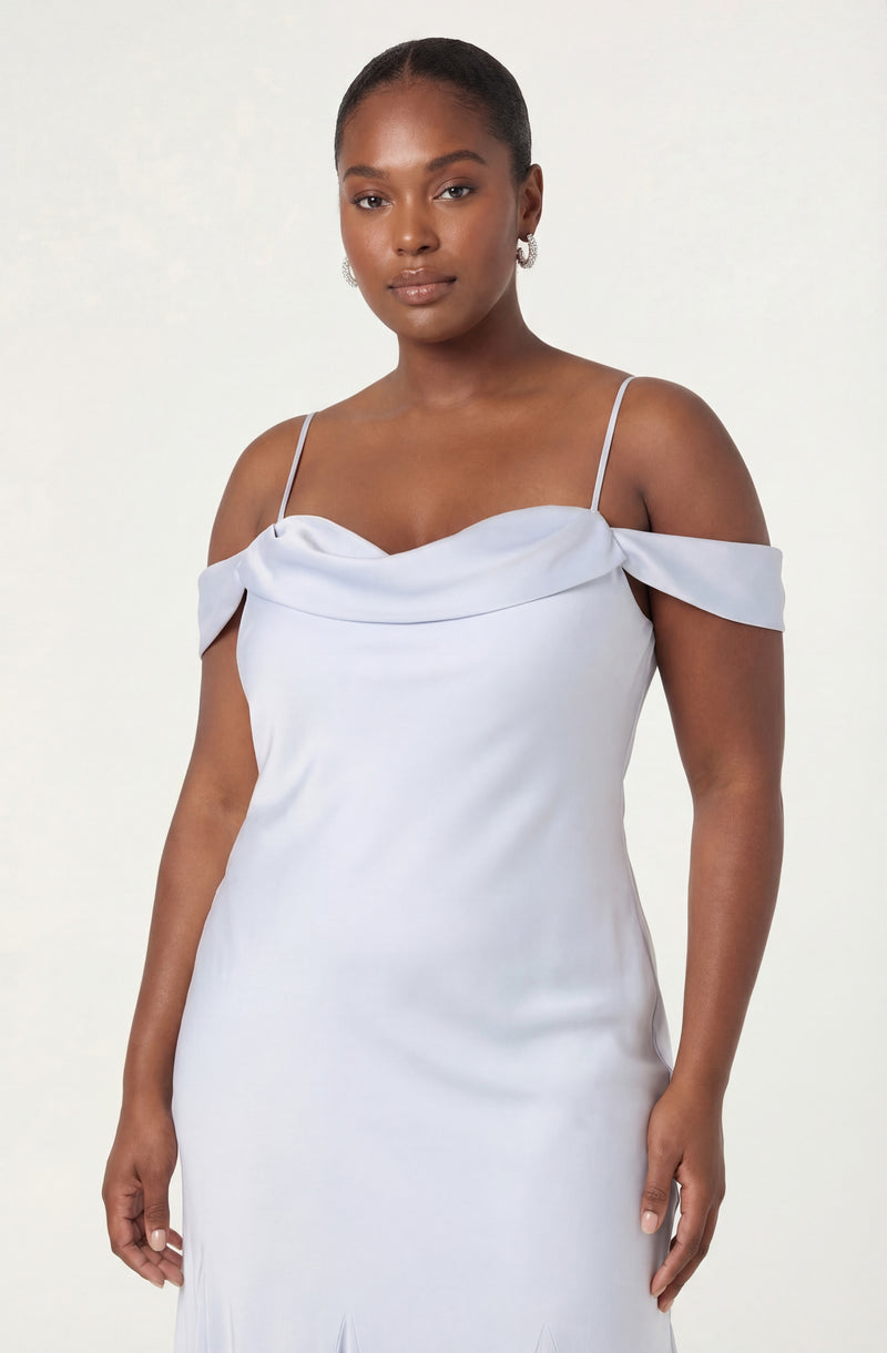 Woman wearing a light blue off-shoulder dress with spaghetti straps and draped fabric detail.