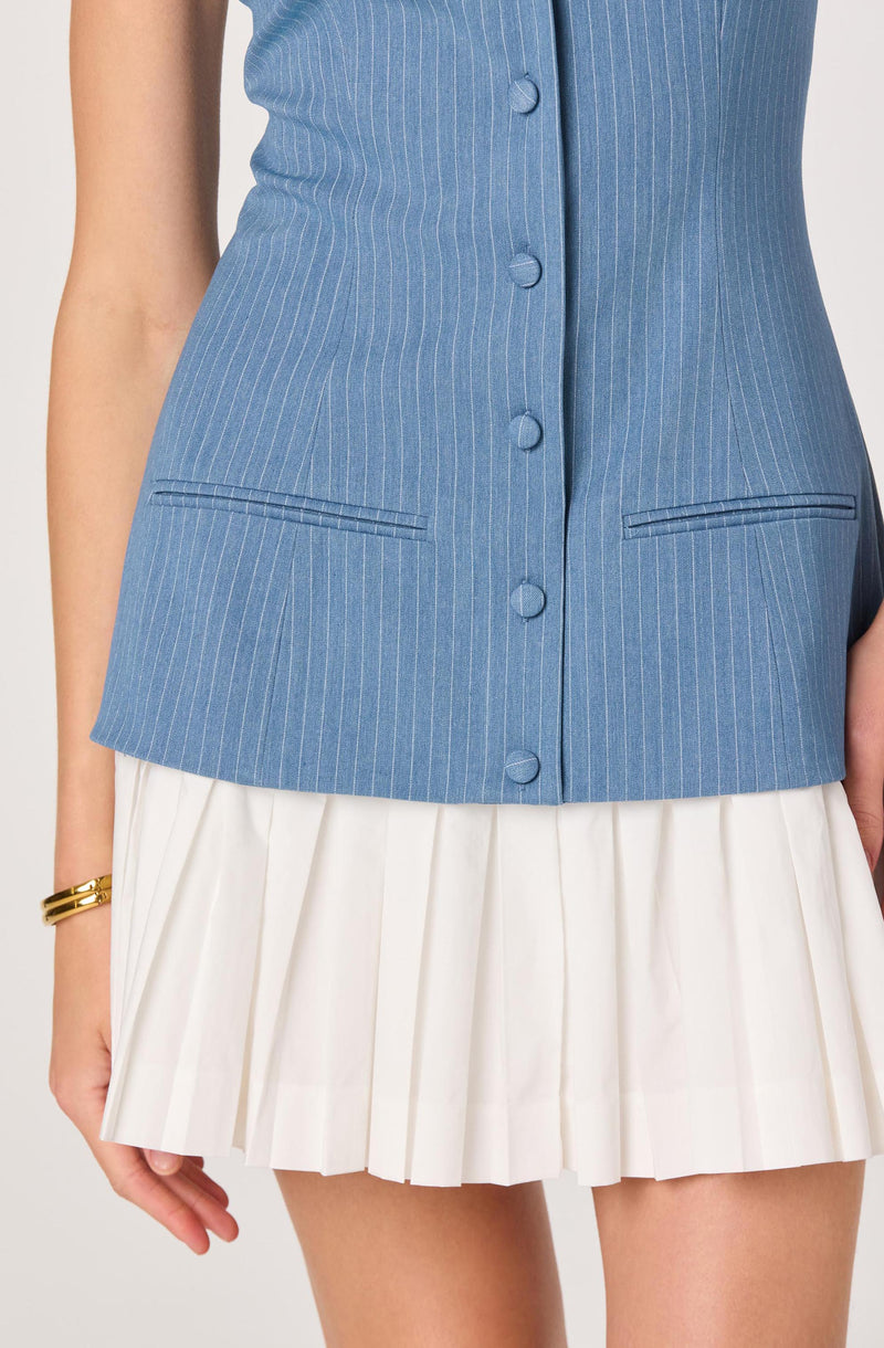 Blue pinstripe vest with buttons, paired with a white pleated skirt.