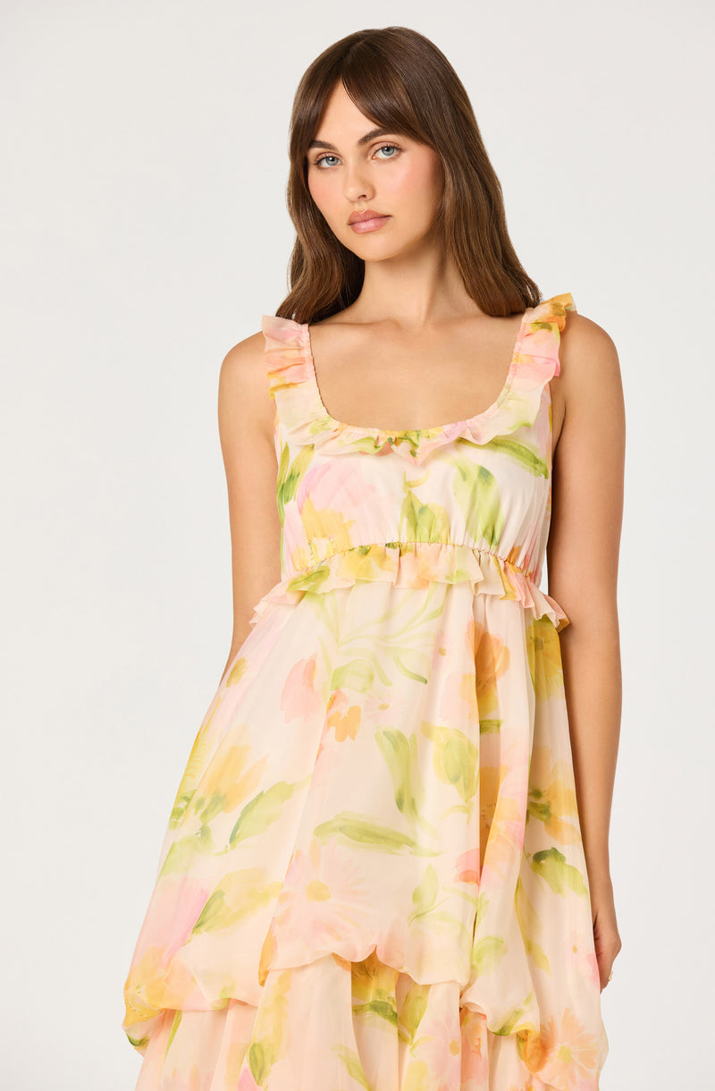Woman in a sleeveless, pastel floral dress with ruffled shoulder straps and a layered skirt.