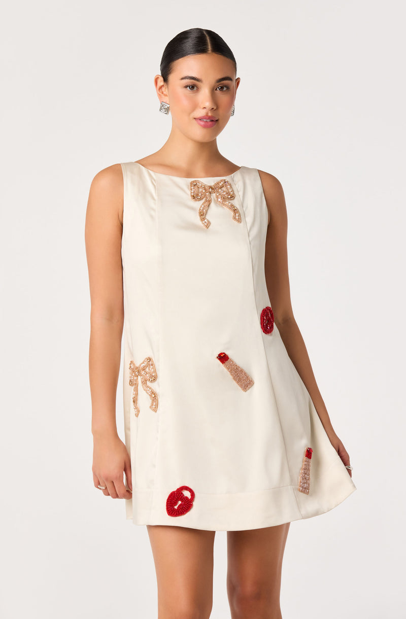 Cream sleeveless dress with embroidered bows, lipstick, and lipstick symbols.