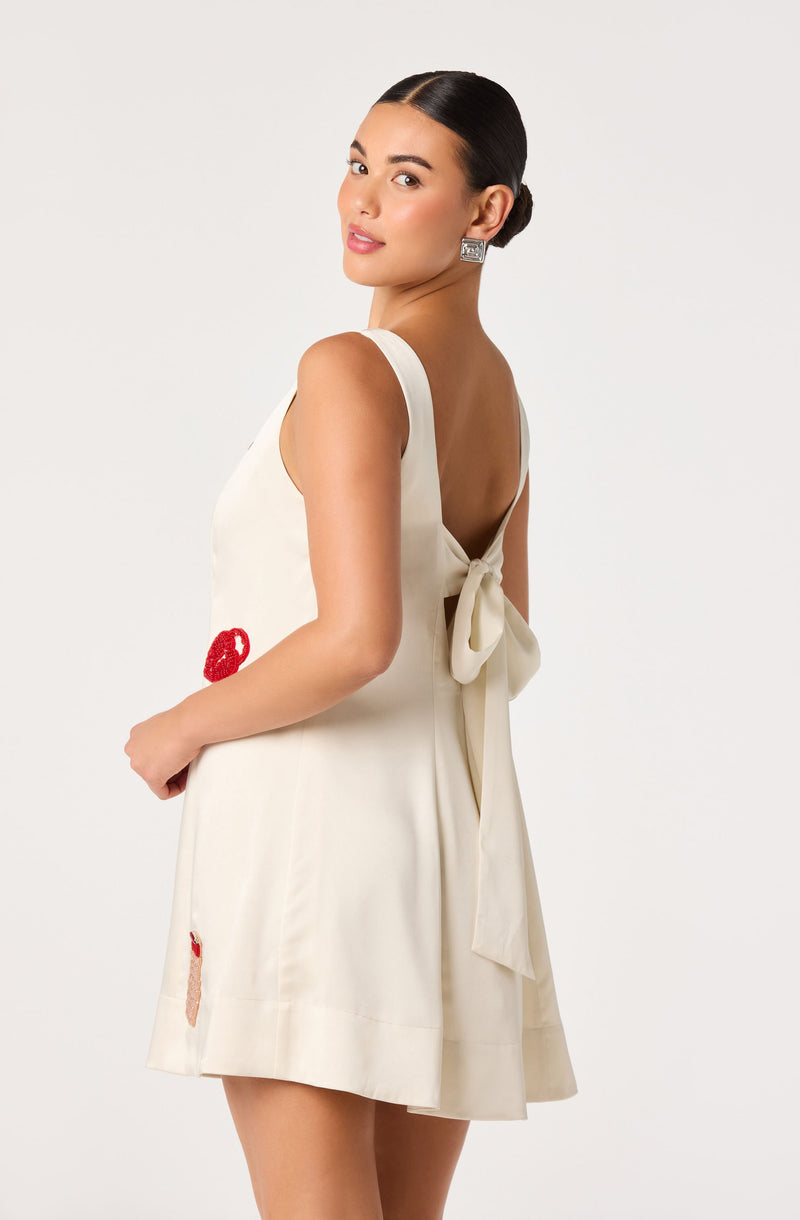 Cream sleeveless dress with a bow at the back and small red embroidered designs.