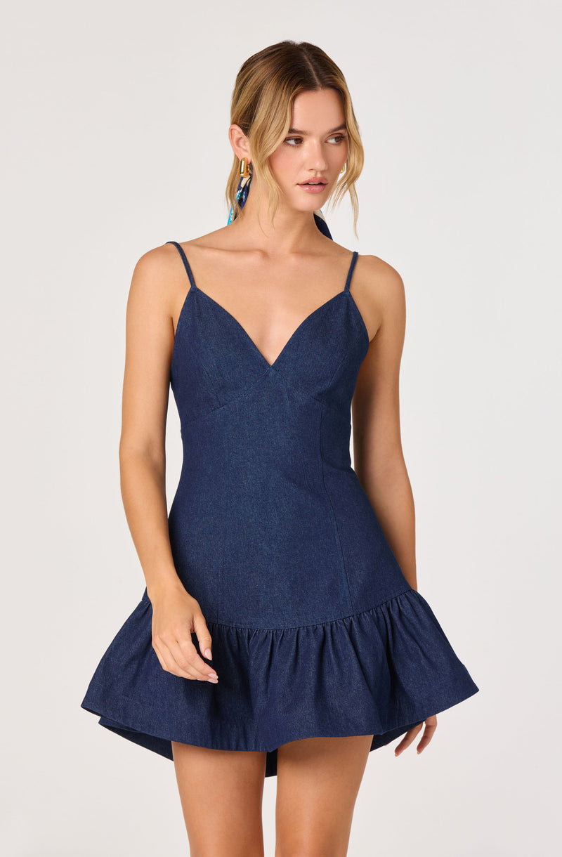 Woman in a sleeveless navy blue denim dress with thin straps and a ruffled hem.