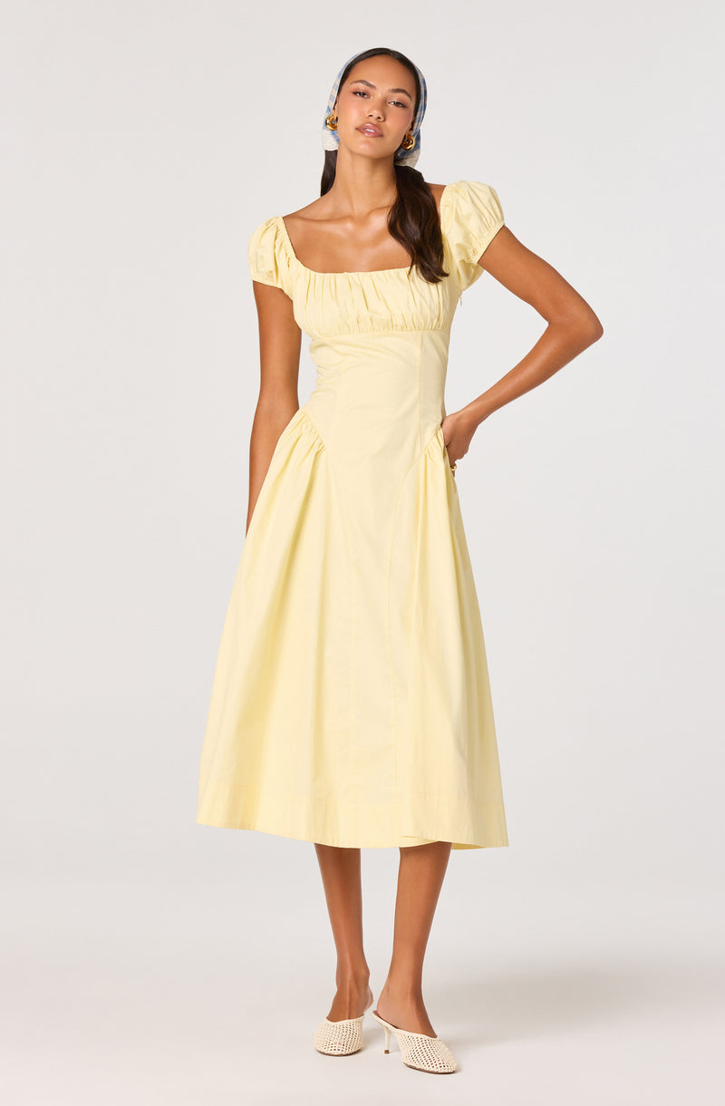 Woman wearing a short-sleeve, yellow, midi-length dress with a gathered neckline and puffed sleeves.