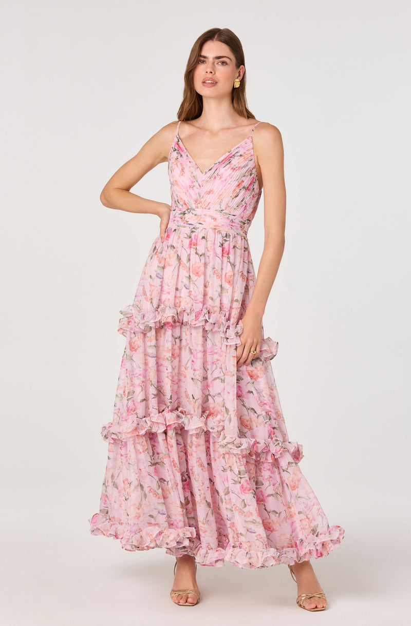 Woman in a pink floral tiered maxi dress with ruffled layers and spaghetti straps.