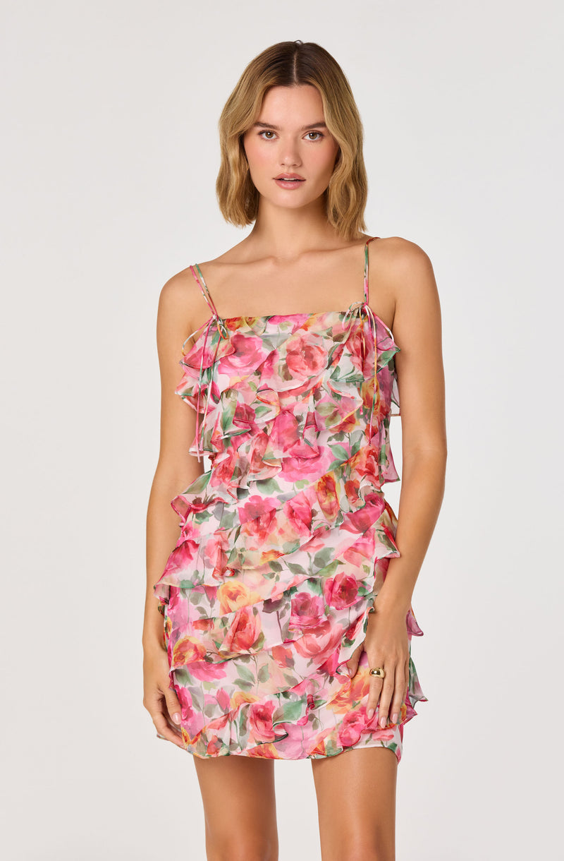 Woman in a pink floral ruffle dress with thin shoulder straps.
