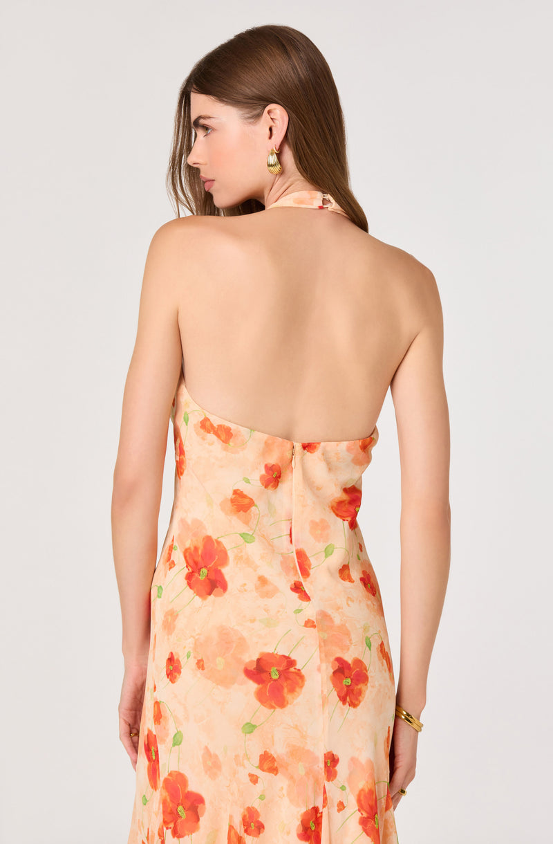 Back view of a woman wearing a strapless dress with a peach background and red-orange floral pattern.
