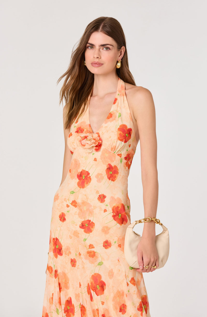 Woman wearing a peach-colored, floral halter dress with large red and orange flowers.
