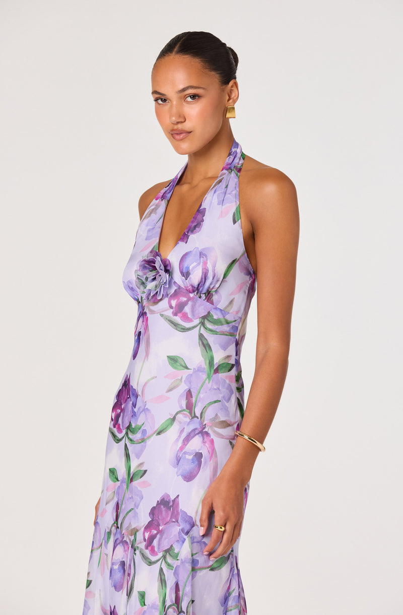 Woman wearing a halter neck floral dress with purple and green watercolor print.