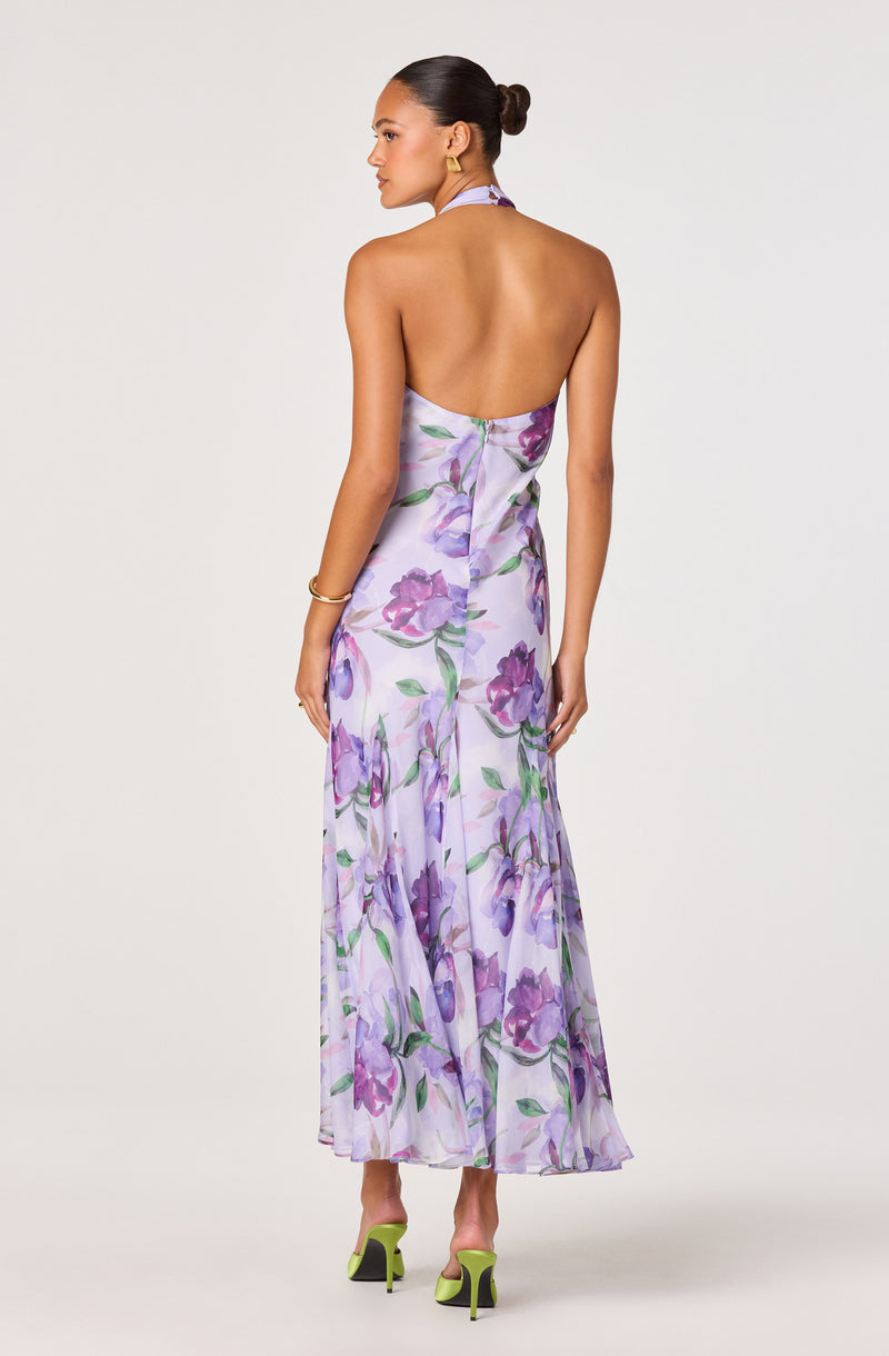 Back view of a woman wearing a strapless, floral, lavender-colored dress with purple flowers and green leaves.