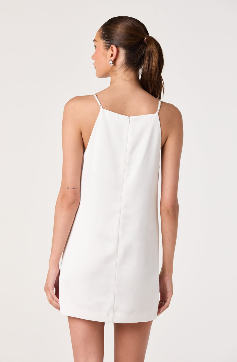 Woman in a white sleeveless dress with thin shoulder straps, back view.