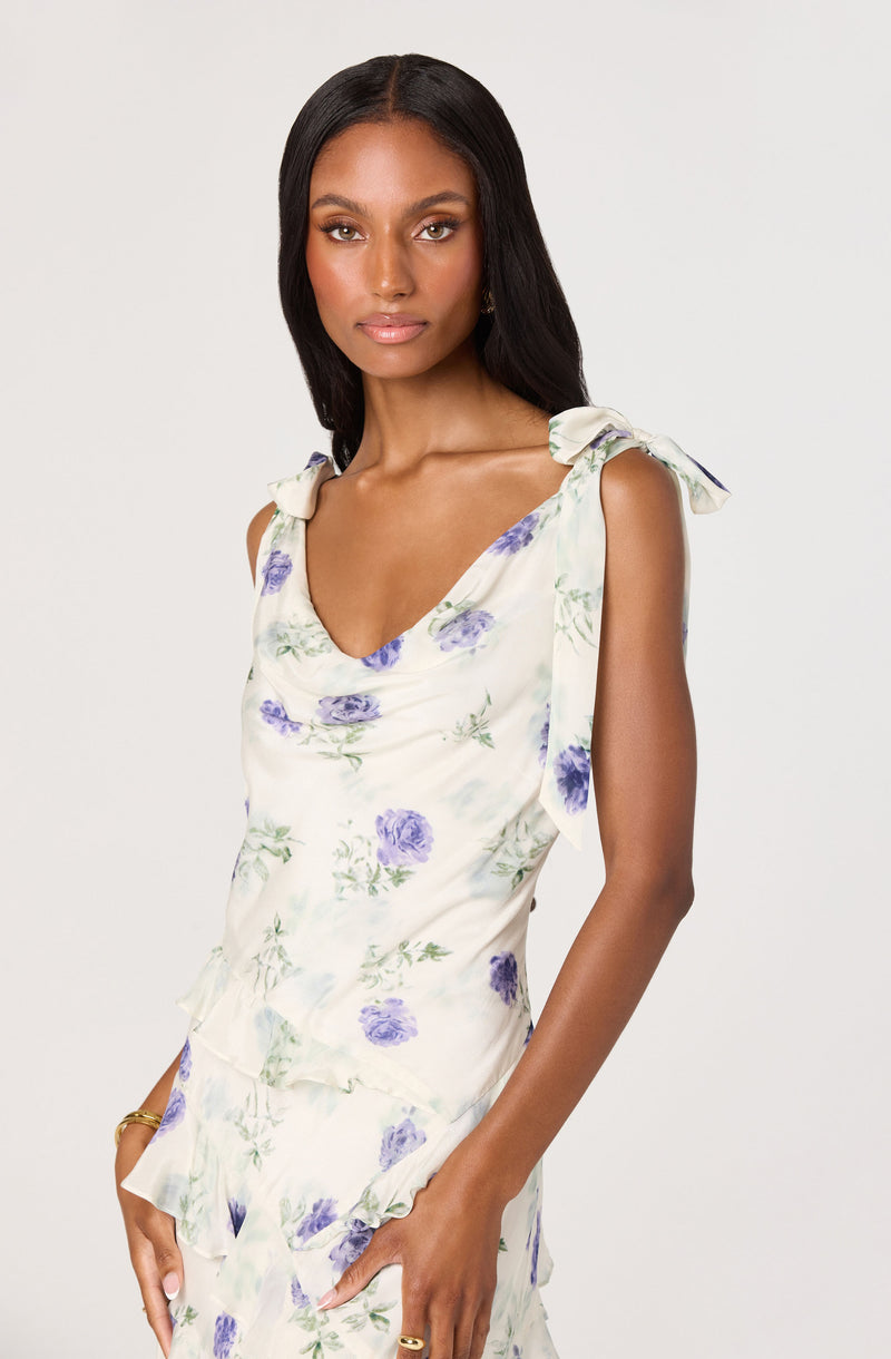 Women wearing sleeveless, floral print top with ruffled shoulder ties and matching skirt.